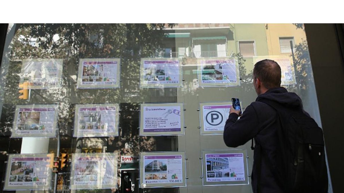Un hombre consulta los anuncios de una inmobiliaria de Barcelona.