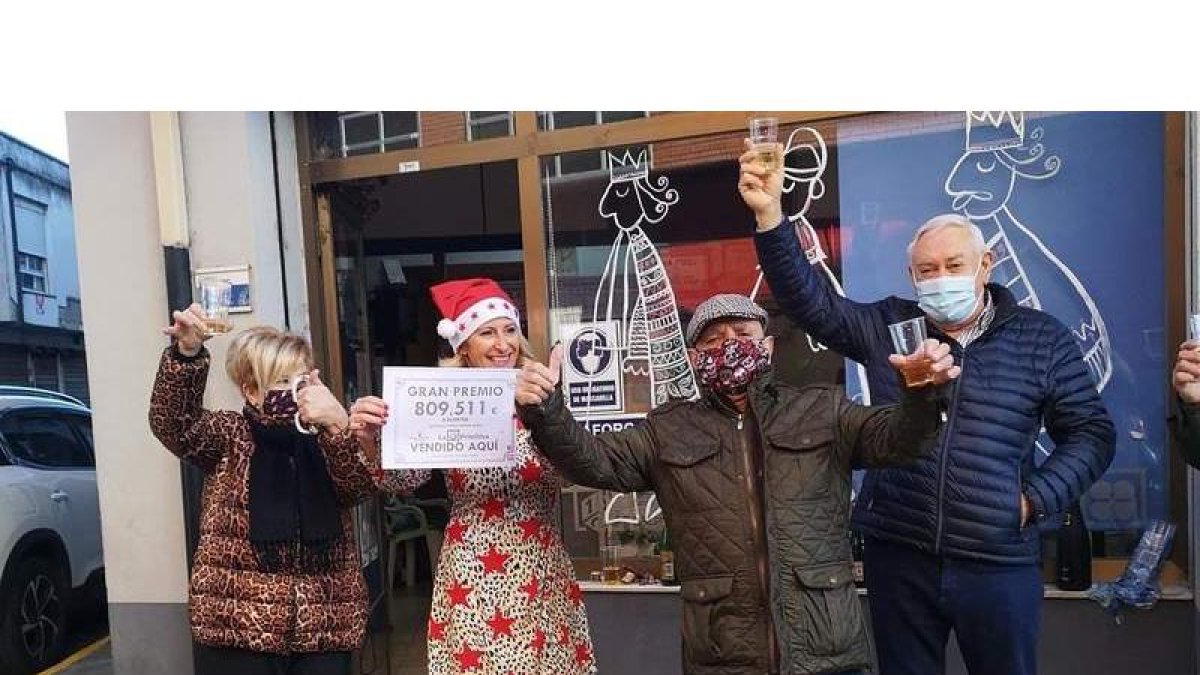 Miembros de la peña celebrando ayer el premio frente a la administración de lotería. DL