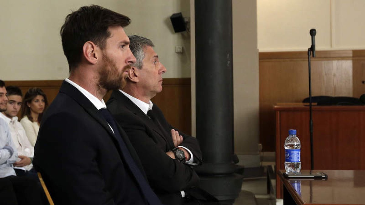 Messi y su padre, ayer, en el banquillo de los acusados durante el juicio por fraude. ALBERTO ESTEVEZ
