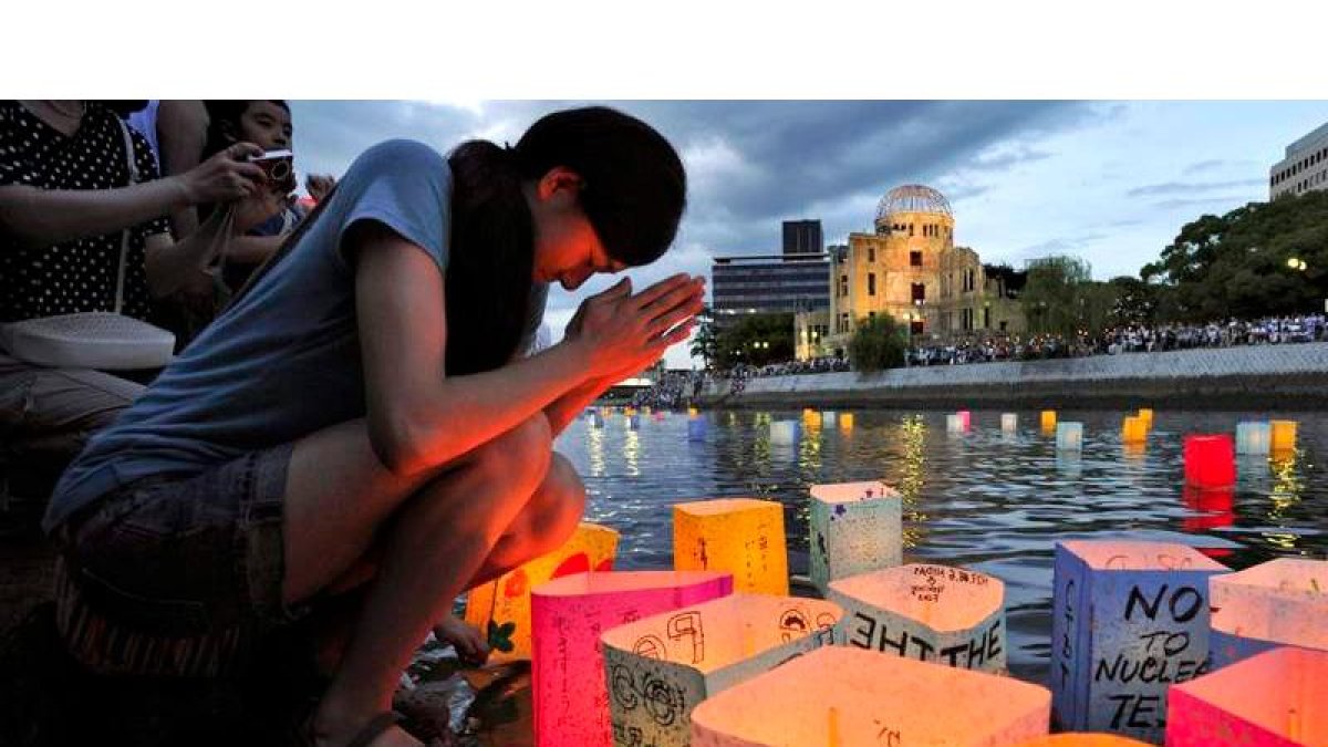 Una joven reza antes de tirar al agua velas en recuerdo de las víctimas de Hiroshima.