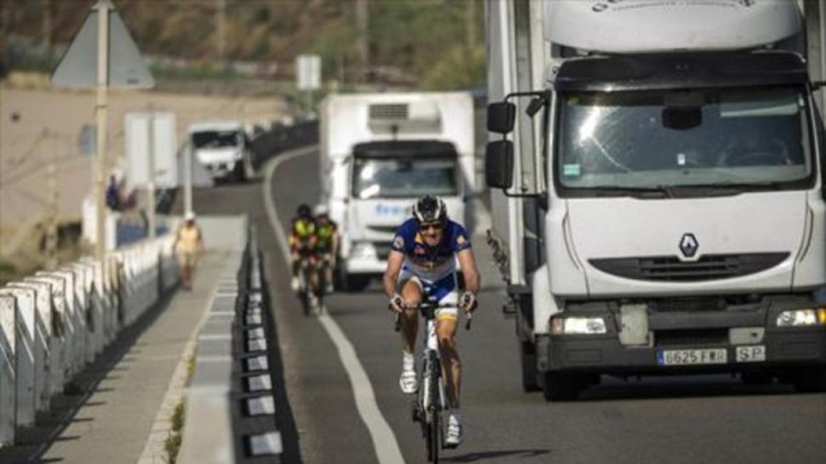 Dos camiones adelantan a unos ciclistas.