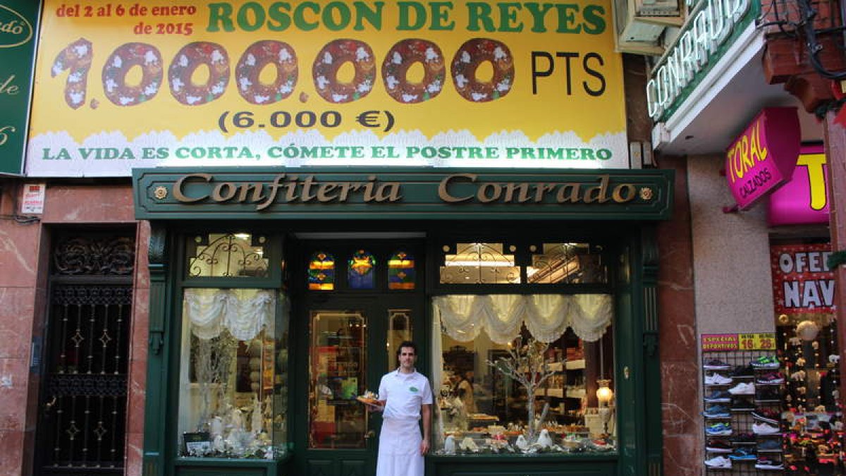 Sergio González, a la puerta de la confitería con un roscón y el enorme cartel con el premio.