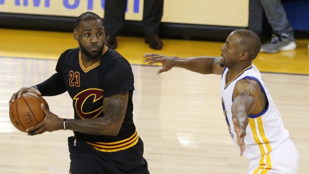 LeBron James trata de supera a Andre Iguodala, en el quinto partido de las finales de la NBA entre Cavaliers y Warriors, el lunes en Oakland.