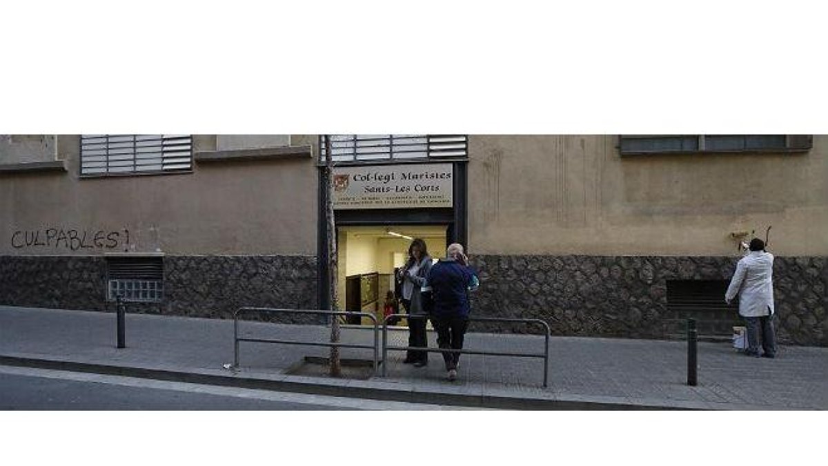 Un hombre borra a las ocho de la mañana las pintadas aparecidas en el colegio de los Maristas de Sants-Les Corts.