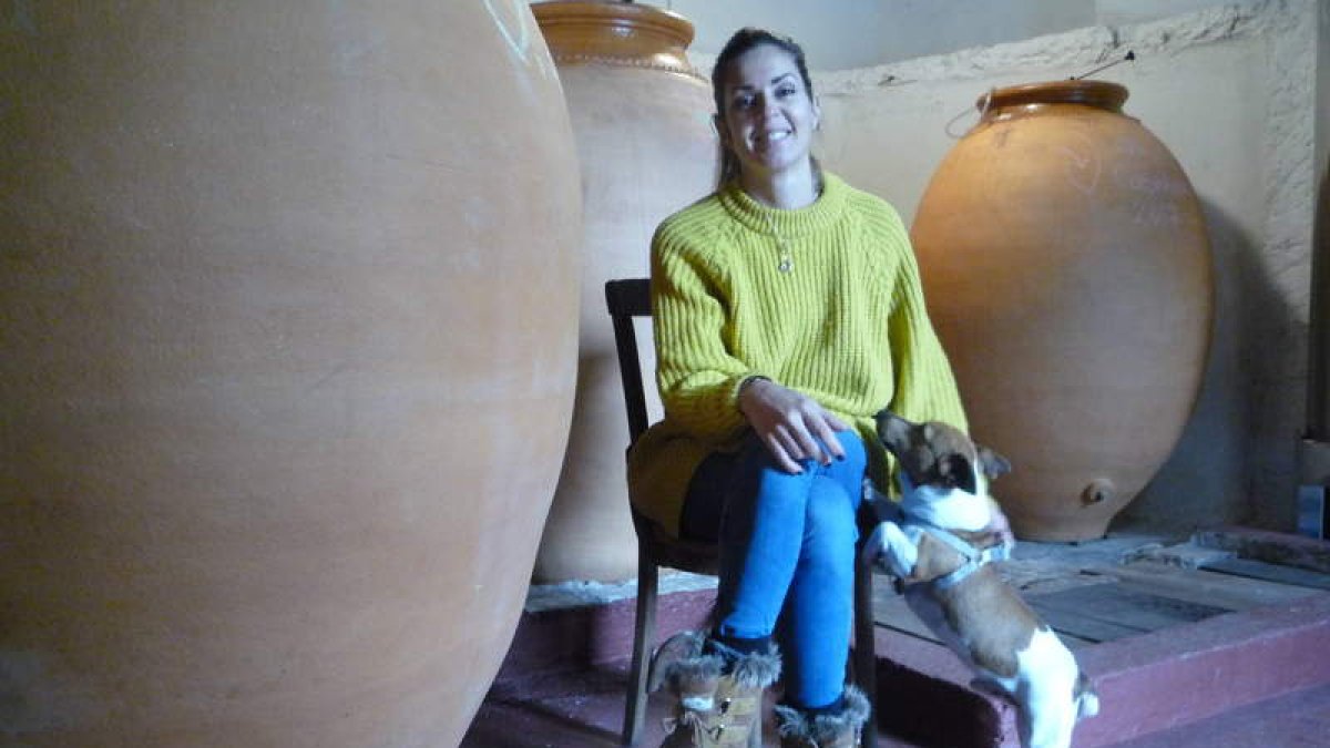 Verónica Orterga, con ‘Enzo’, su leal e inseparable compañero, entre las ánforas de su bodega en Valtuille de Abajo. B. FERNÁNDEZ