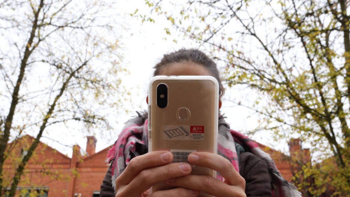 Una joven utiliza su teléfono móvil junta a un instituto de la capital vallisoletana. RUBÉN CACHO