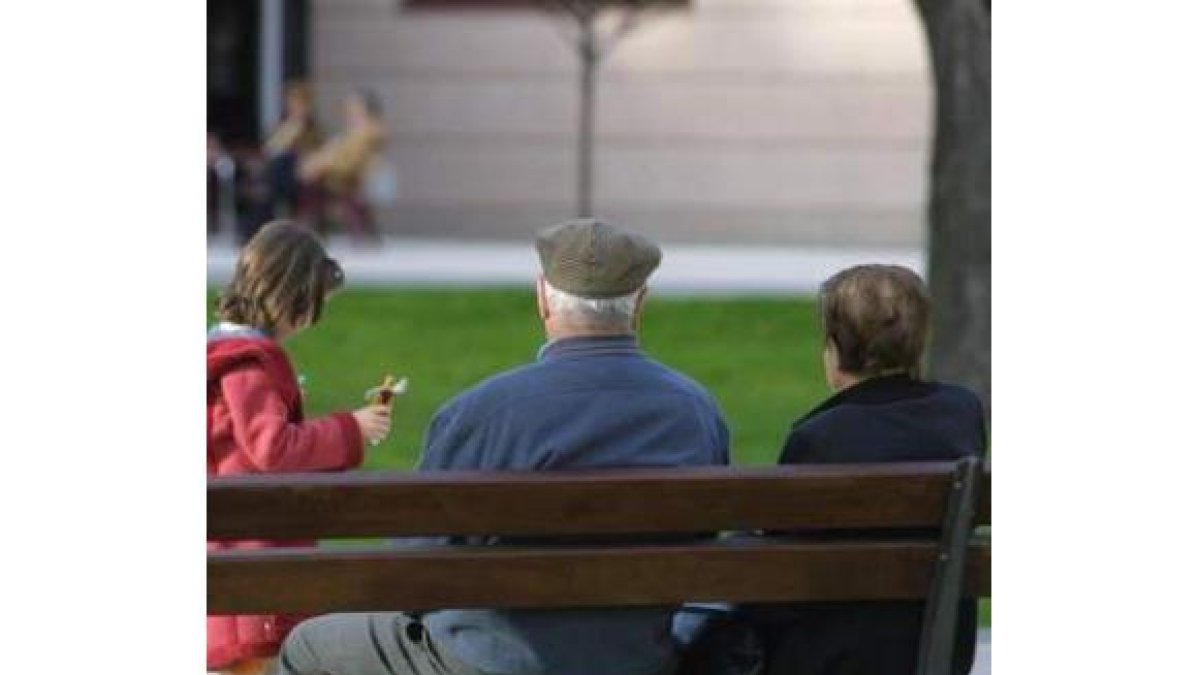 Unos ancianos sentados en un banco junto a su nieta.