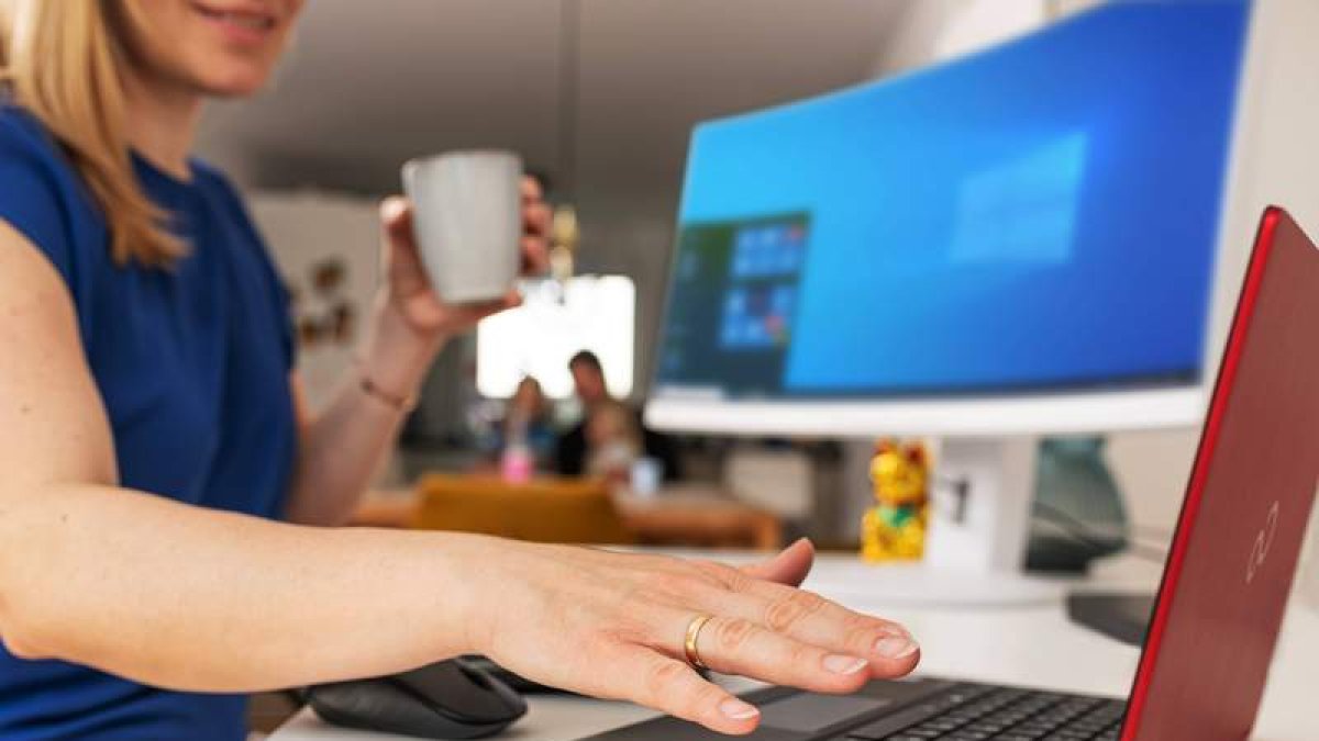 Mujer mira su portátil mientras trabaja desde casa usando el sistema Palm Secure. fujitsu