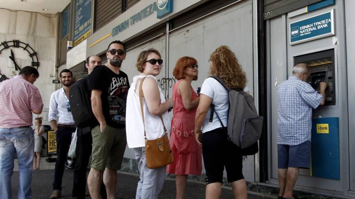 Atenienses hacen cola ayer para retirar dinero de un cajero automático en una sucursal del Banco Nacional de Grecia, en Atenas (Grecia).