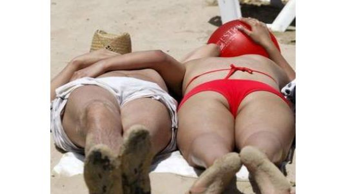 Unos turistas toman el sol en Alicante.