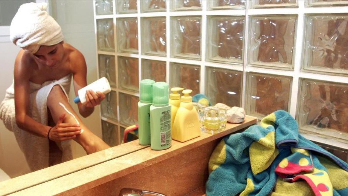 Una mujer se aplica aftersun en el baño.