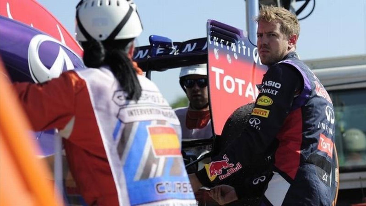 Vettel ayuda a subir su coche a la grúa tras poder completar solo cuatro vueltas en los entrenamientos matutinos del circuito de Montmeló.