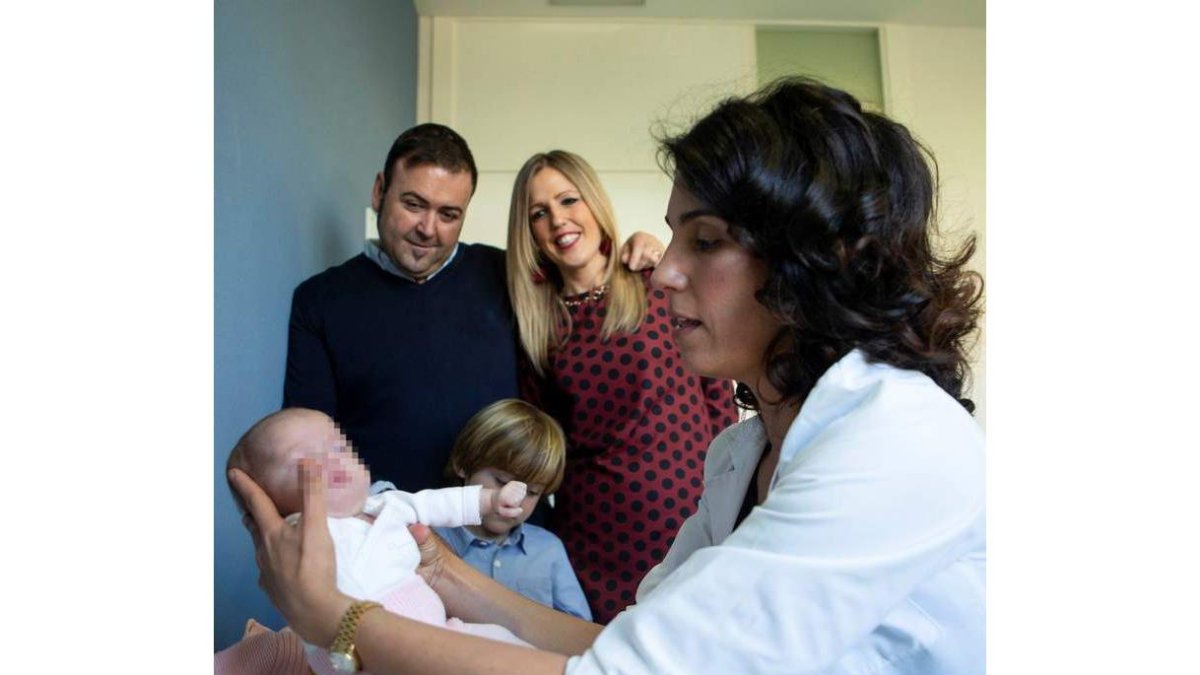 La doctora Georgia Sarquella con la bebé y la familia de fondo. ENRIC FONTCUBERTA