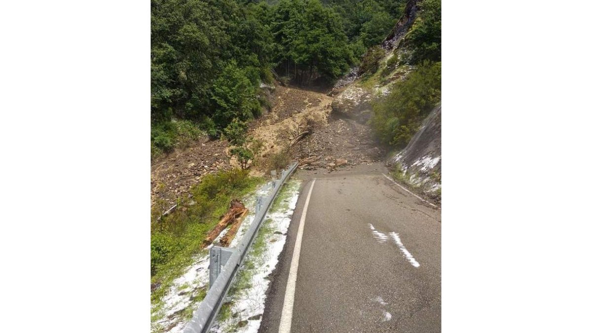 El granizo era visible ayer en la cuneta de la carretera de Peñalba, poco después del desprendimiento de tierra y lodo causada por la tormenta en la misma curva del vial LE-5238 de siempre. DL