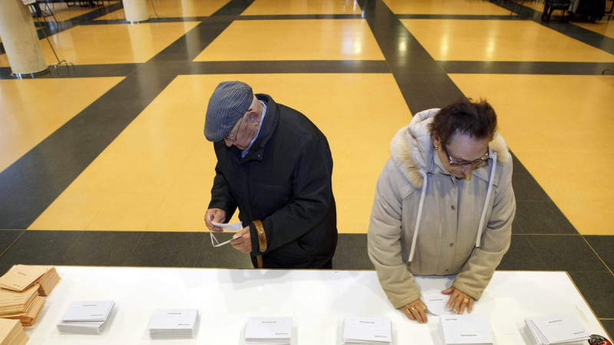 Dos ciudadanos escogen sus papeletas en el colegio electoral.
