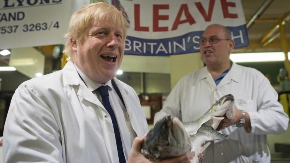 Un exultante Boris Johnson (izquierda) sostiene un salmón salvaje junto a Greg Essex, en el mercado de pescado de Billingsgate, en Londres, este miércoles.
