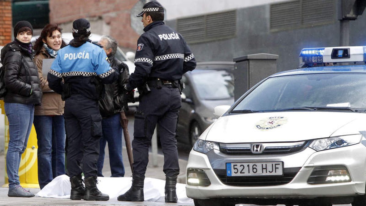 Agentes de la Policía Local custodian el cadáver, que yace tendido en la acera tapado con una sábana.