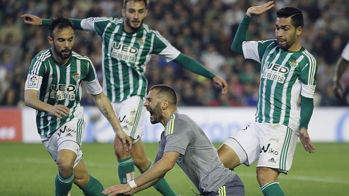 El delantero francés del Real Madrid, Karim Benzema, cae al suelo ante los jugadores del Betis.