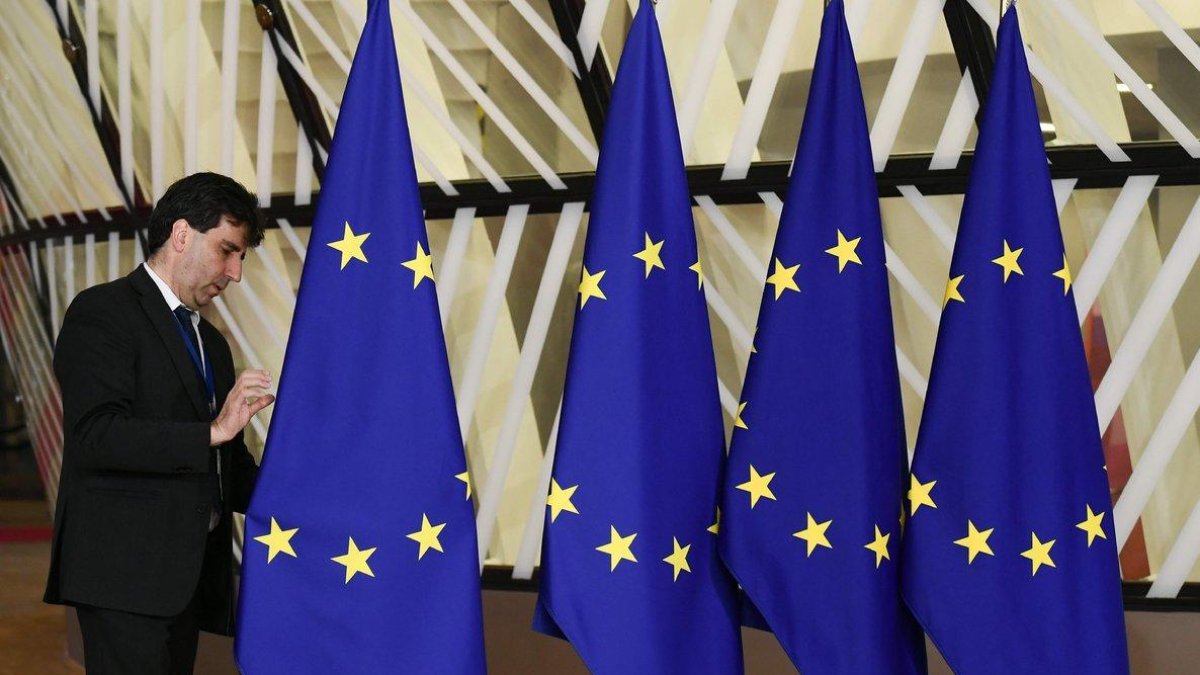 Un funcionario prepara las banderas de la Unión Europea antes del inicio de la cumbre, este domingo en Bruselas.