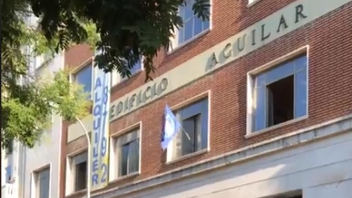 El emblema de Hogar Social Madrid ondea en una de las ventanas del nuevo edificio okupado, las antiguas oficinas de la Editorial Aguilar. /