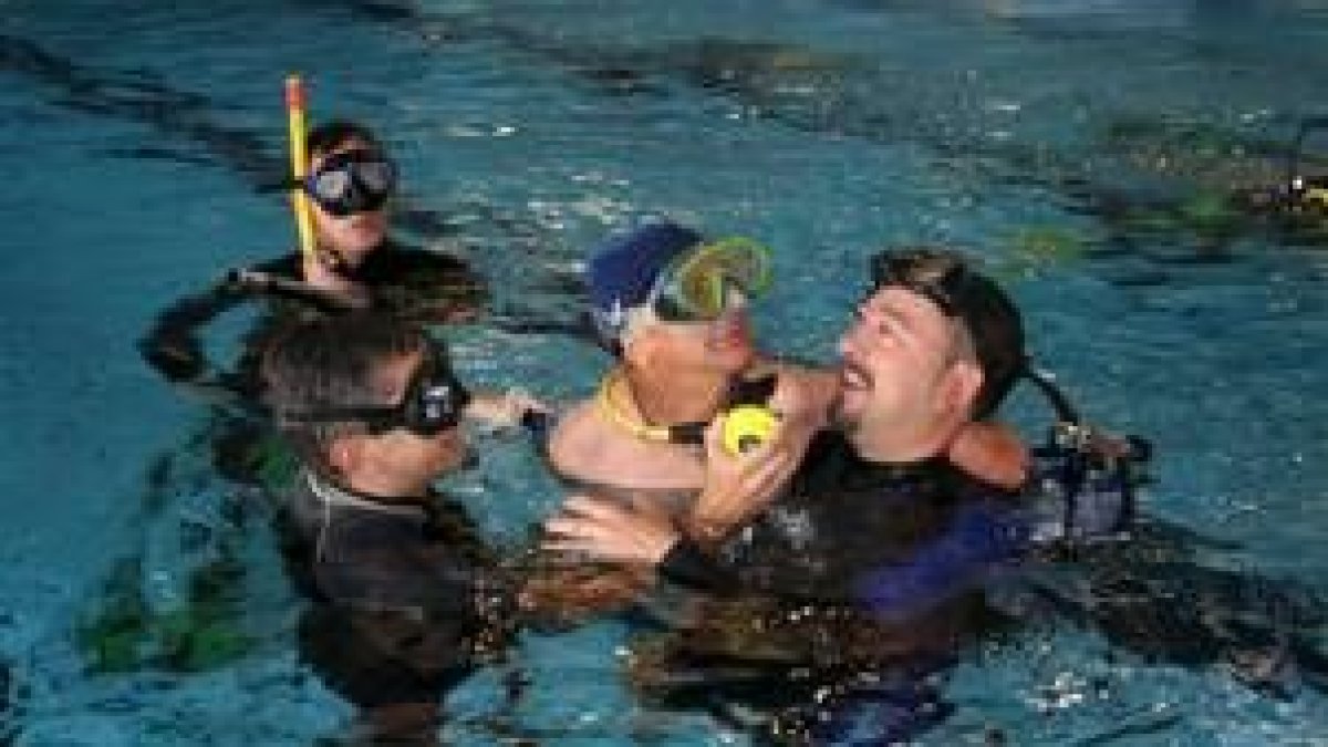Uno de los alumnos discapacitados disfruta de su momento en el agua acompañado de los monitores
