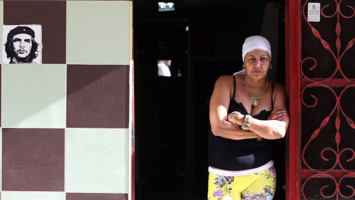 Una mujer permanece en la puerta de su casa en La Habana junto a una imagen del Che Guevara