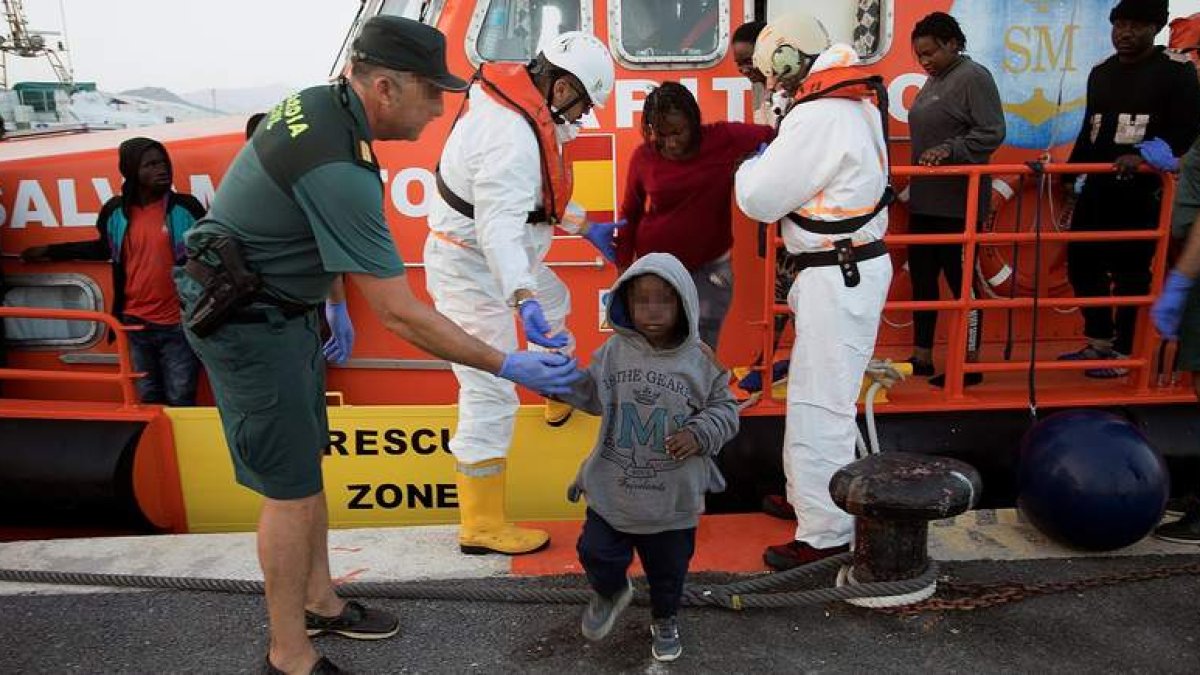 Un guardia civil ayuda a un niño que llegó en una patera a las costas españolas. MIOGUEL PAQUET