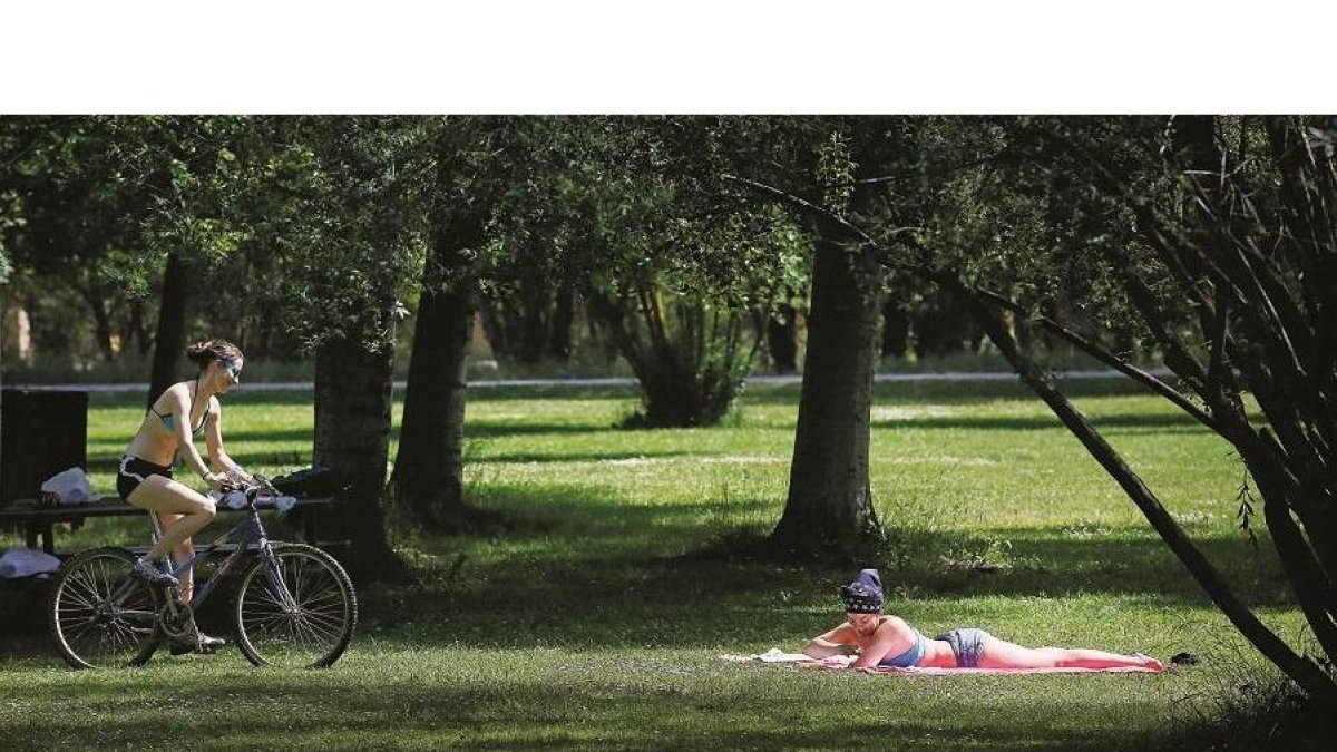 Unas jóvenes se alivian de los calores estivales en el parque de La Candamia de la capital.
