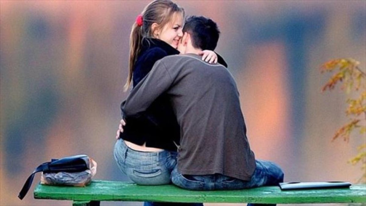 Una pareja de jóvenes se abraza en un parque.