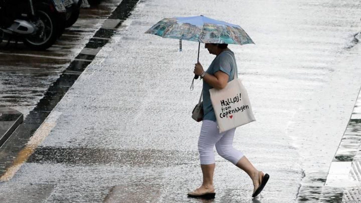 na persona se resguardan con el paraguas en plena tormenta a primeras horas de hoy en Valencia.
