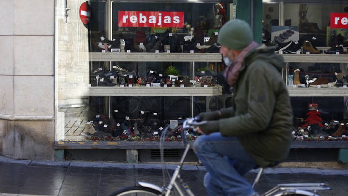 Un hombre pasa frente a un escaparate comercial de León. FERNANDO OTERO