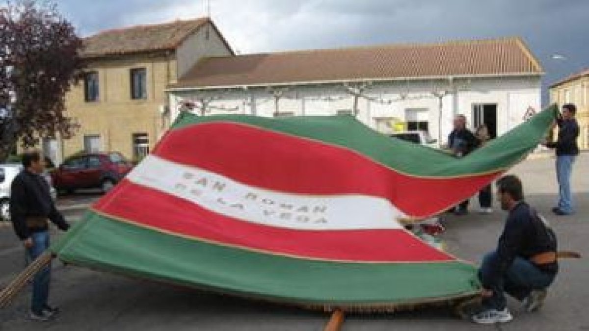 Los mozos preparan el pendón para la puja, luchando contra el viento.