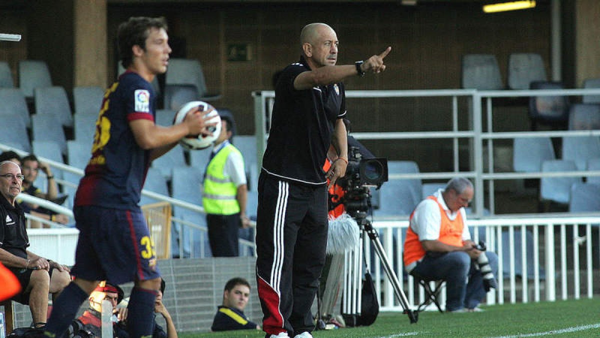 Claudio da instrucciones a sus jugadores desde su zona técnica mientras un futbolista del Barcelona B se dispone a sacar el balón de banda.