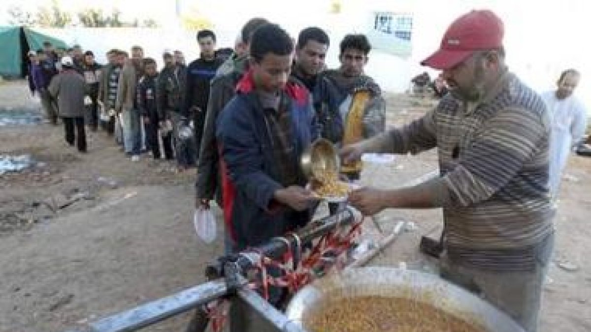 Egipcios hacen cola para recibir comida en el paso fronterizo de Ras el Jedir (Túnez).