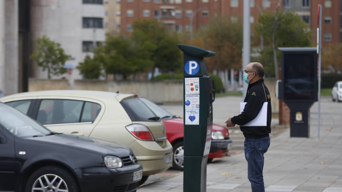 Una persona mete monedas en una máquna de la ORA en León. FERNANDO OTERO