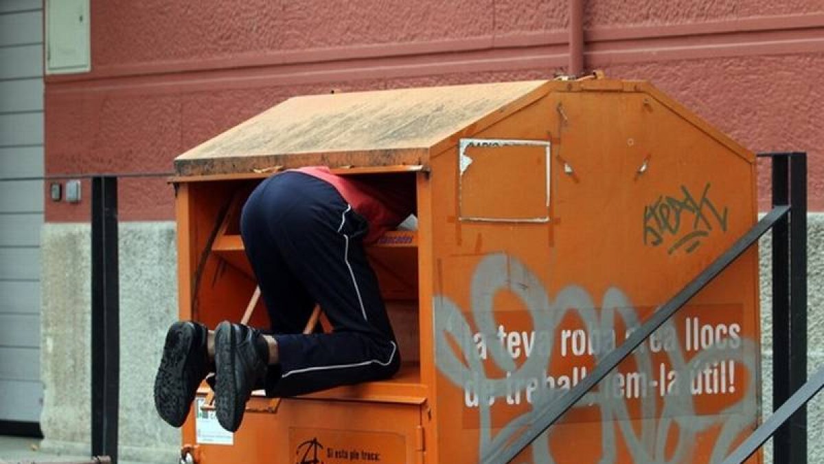 Un hombre rebusca dentro del contenedor de una oenegé.