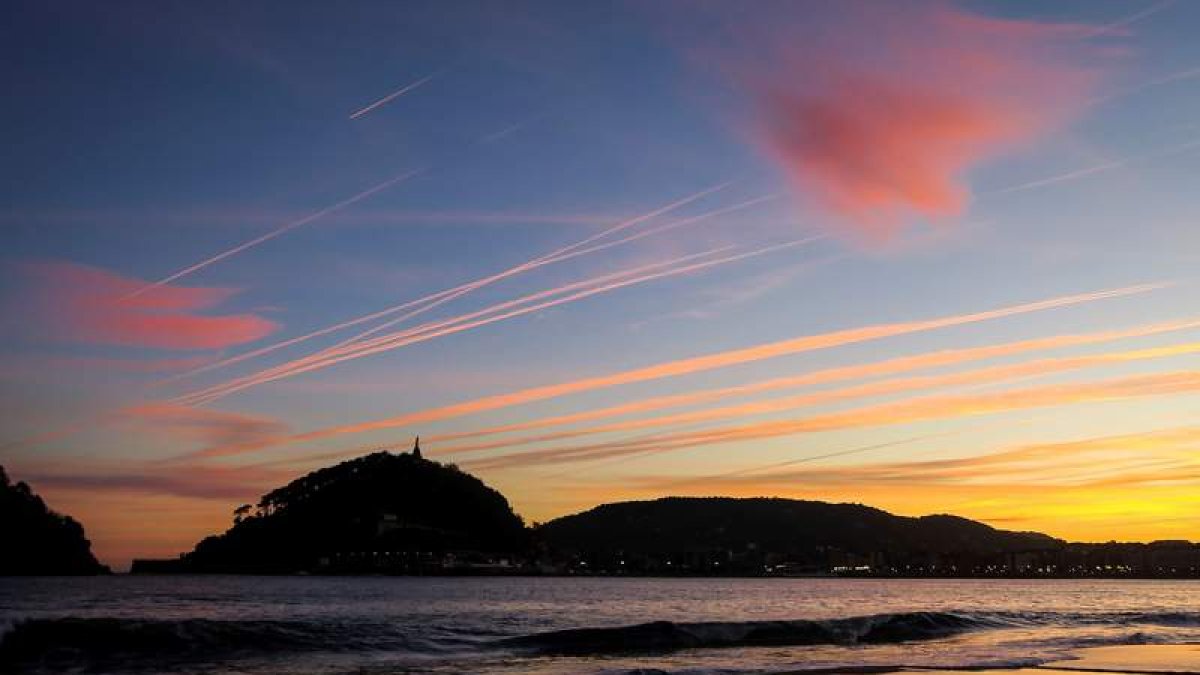 Un hombre observa el amanecer en la playa de Ondarreta de San Sebastián.