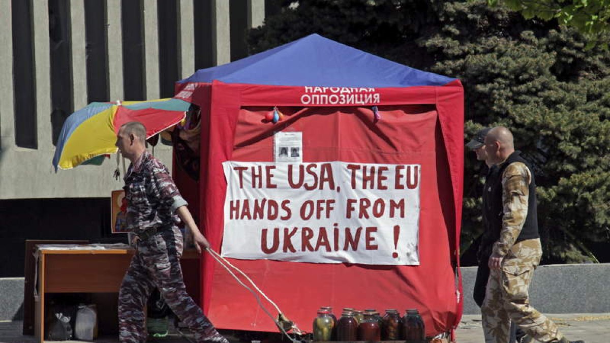 Activistas prorrusos pasan delante de una pancarta contra EE UU y la UE en Ucrania.