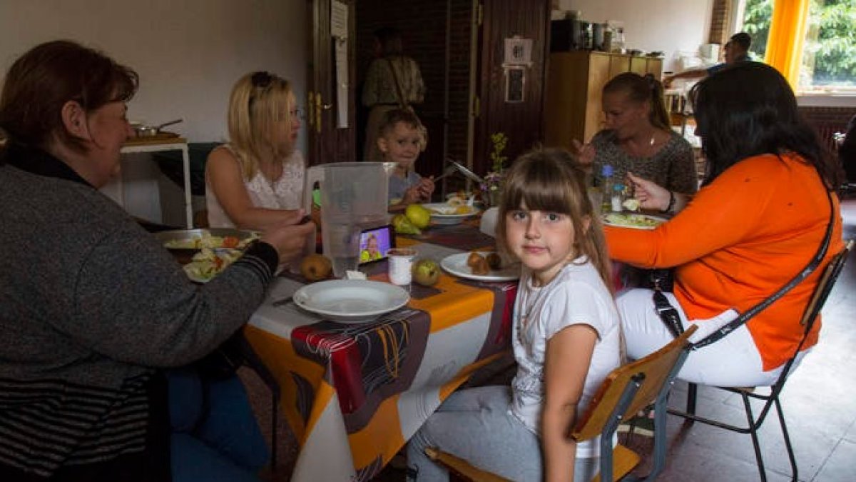 Varias familias ucranianas comparten la mesa en el comedor del colegio de La Nora del Río. FERNANDO OTERO