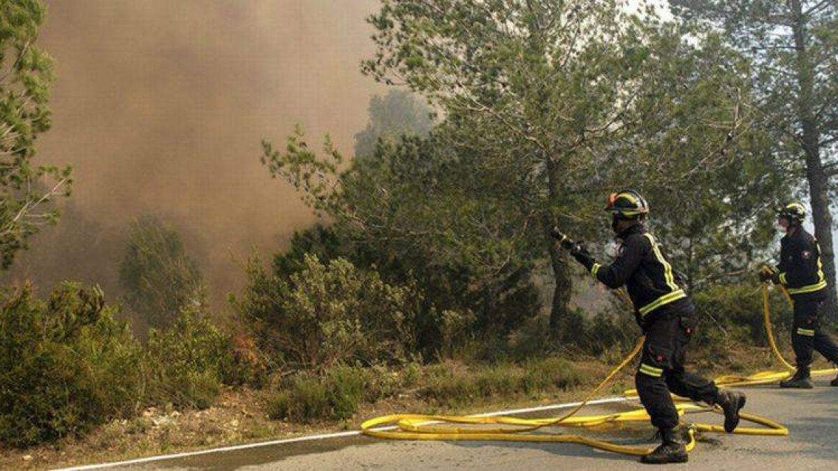 Dos efectivos del cuerpo de Bomberos durante las labores de extinción del incendio declarado en la zona de Es Cubells, en el municipio ibicenco de Sant Josep de sa Talaia.