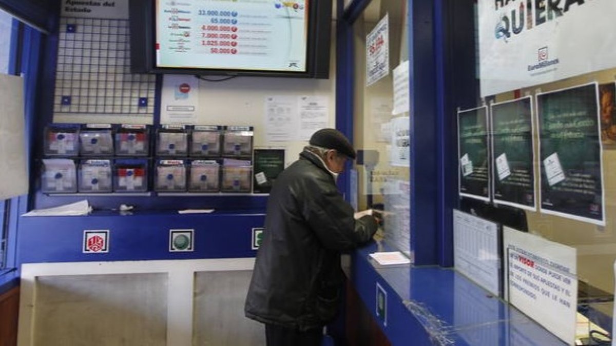 Un hombre sella un boleto en una administración de lotería. J. F. S.