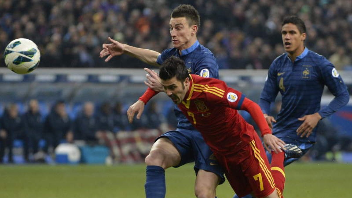 David Villa lucha por el balón con el defensa francés Laurent Koscielny durante el partido clasificatorio contra Francia.
