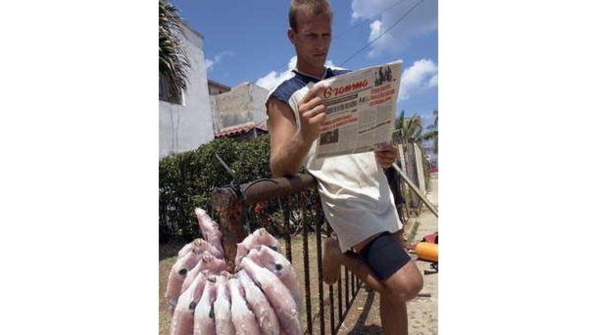 Un hombre lee en el diario oficial Granma las reflexiones de Fidel Castro