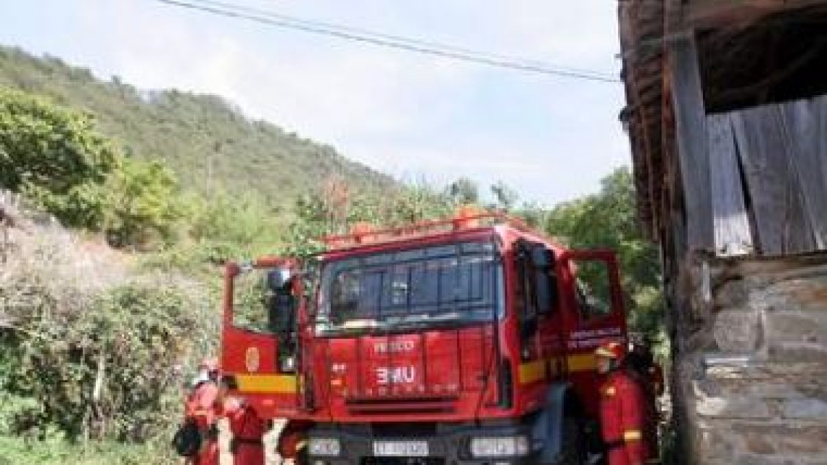 Un helicóptero descarga agua en una ladera del monte de roble situado justo por encima de las casas