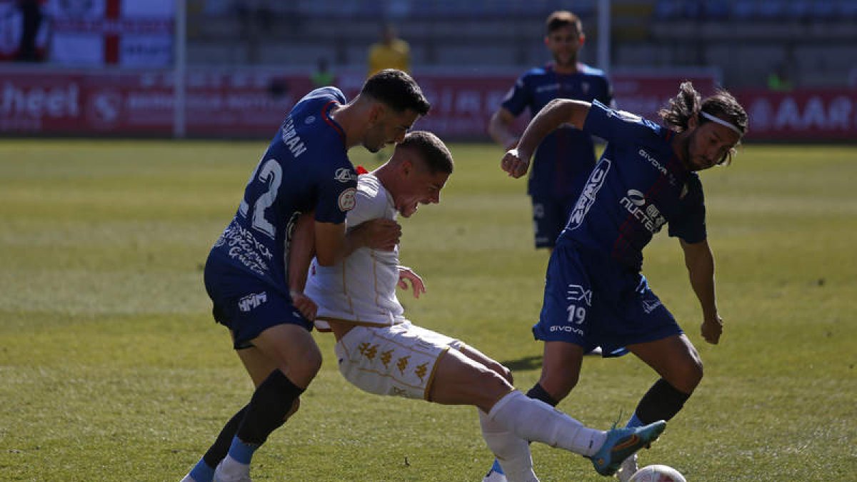 El lateral derecho visitante Albarrán frena al local Roberto Alarcón en un lance del encuentro con el exculturalista Mario Ortiz muy pendiente del balón. FERNANDO OTERO
