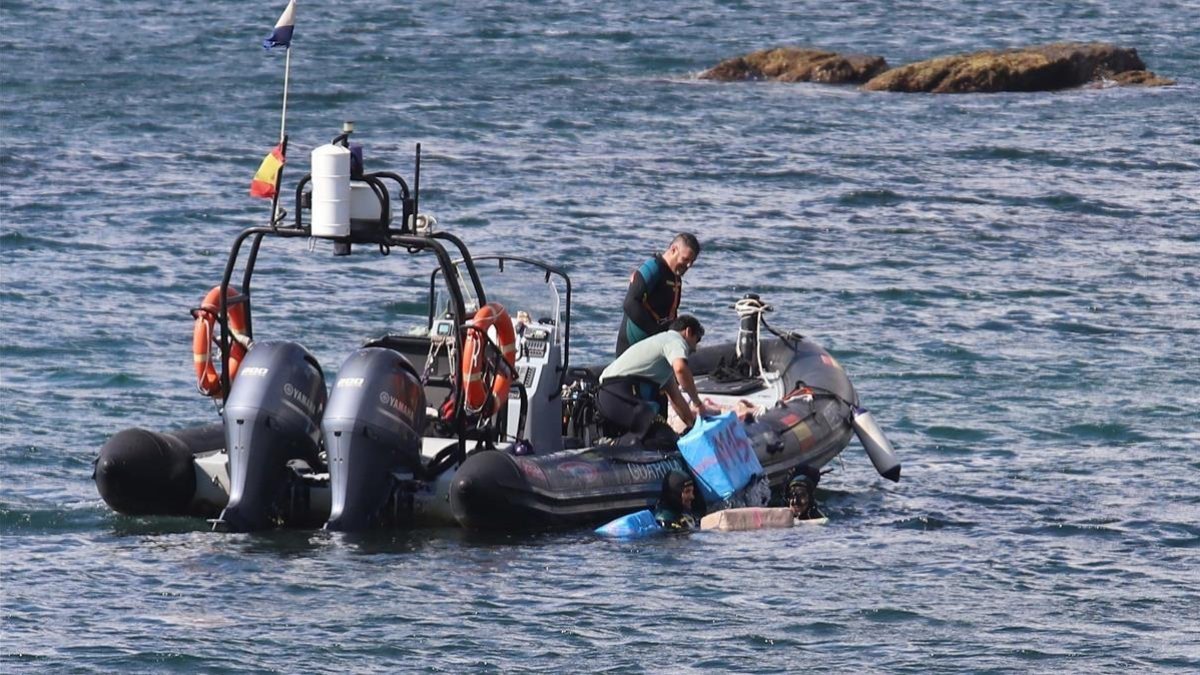 Agentes de la Guardia Civil recogen del agua fardos de hachís en la zona de San García, en Algeciras (Cádiz).
