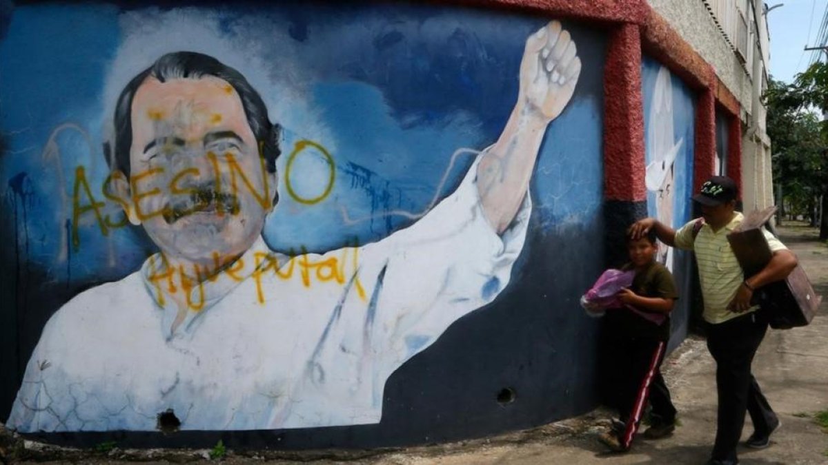 Dos personas pasan junto a un mural de Daniel Ortega en Managua