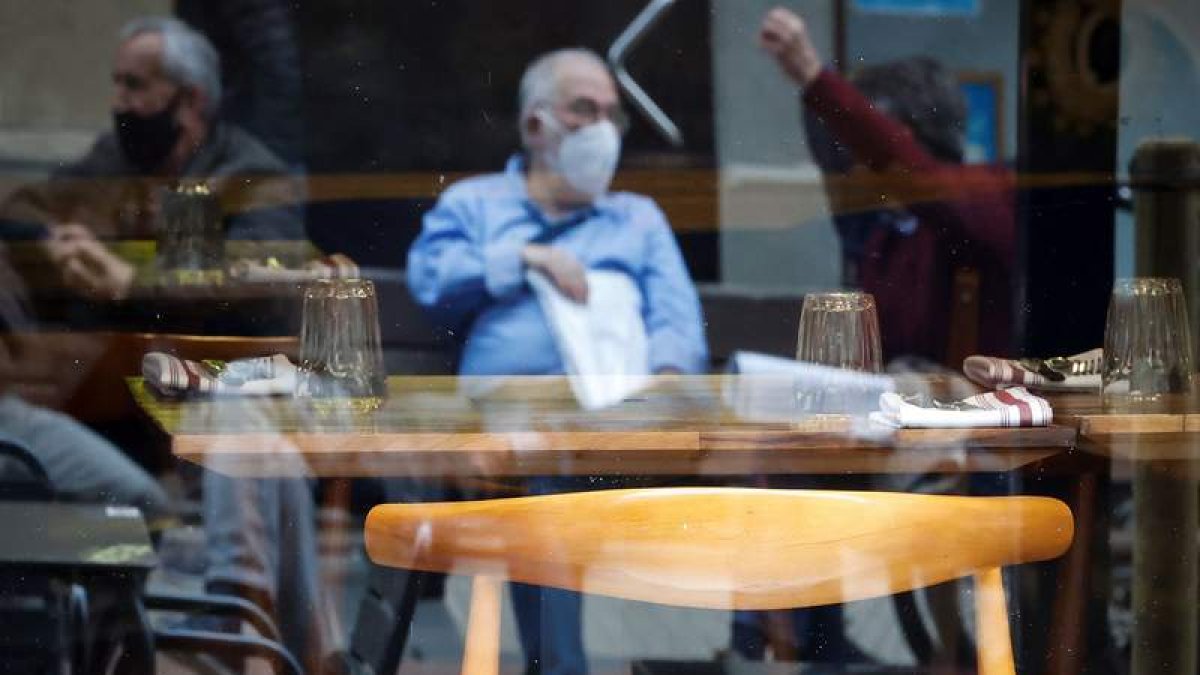 Varios hombres conversan junto a un restaurante vacío en San Sebastián, ayer. JAVIER ETXEZARRETA