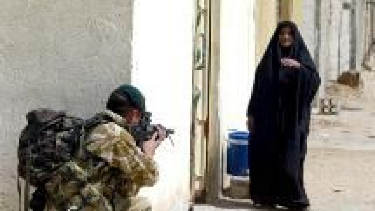 Un soldado británico apunta con su arma a una anciana en una calle de Umm Qasr, en el sur iraquí