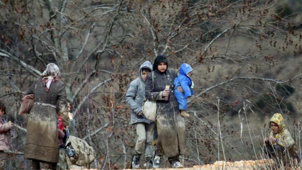 Refugiados sirios, cubiertos de barro, junto a la frontera con Turquía.